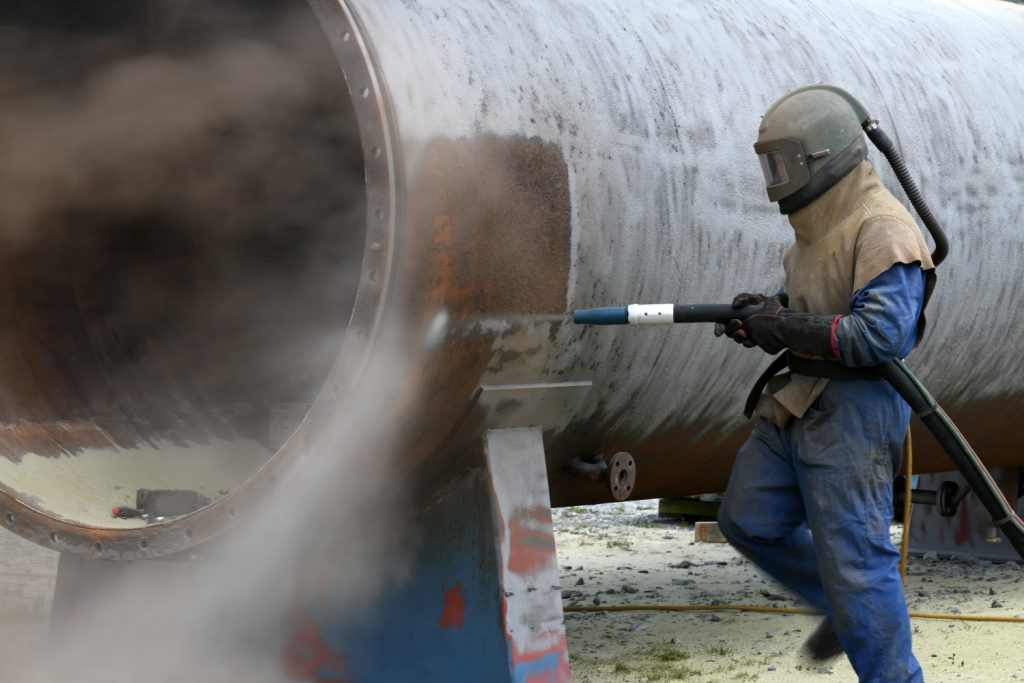 A man is spraying a pipe.