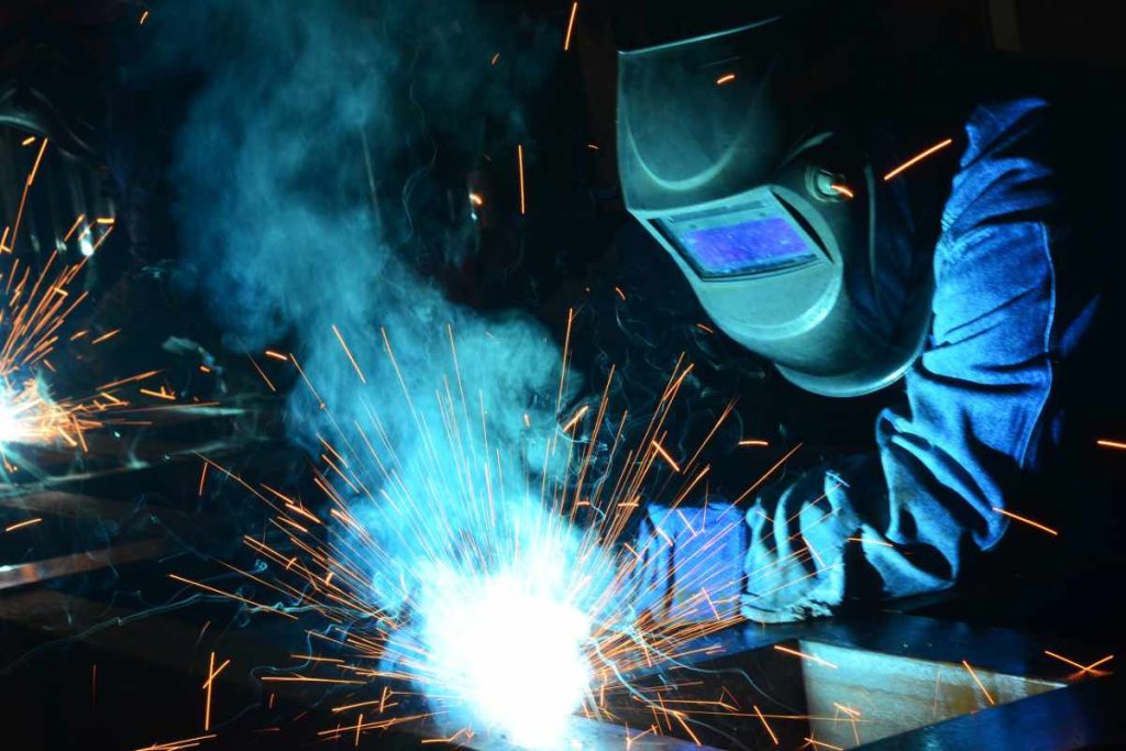 A welder working with sparks in a dark room.