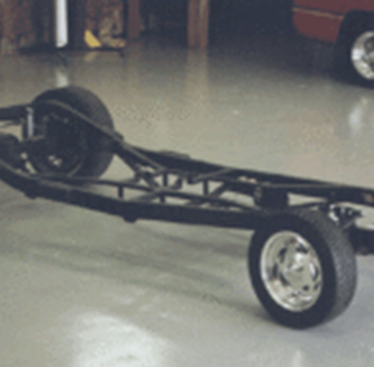 A car frame with wheels and tires on the floor.